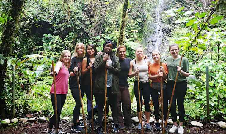 Hiking group posing next to waterfall.